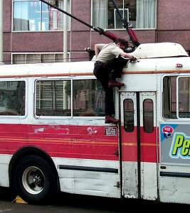 Your roving SF reporter spotted this bus-driver clambering onto his roof to free his trapped electricity pick-ups